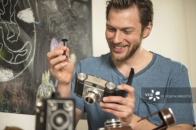 在德国巴伐利亚慕尼黑，男人在餐厅修理古董相机图片素材