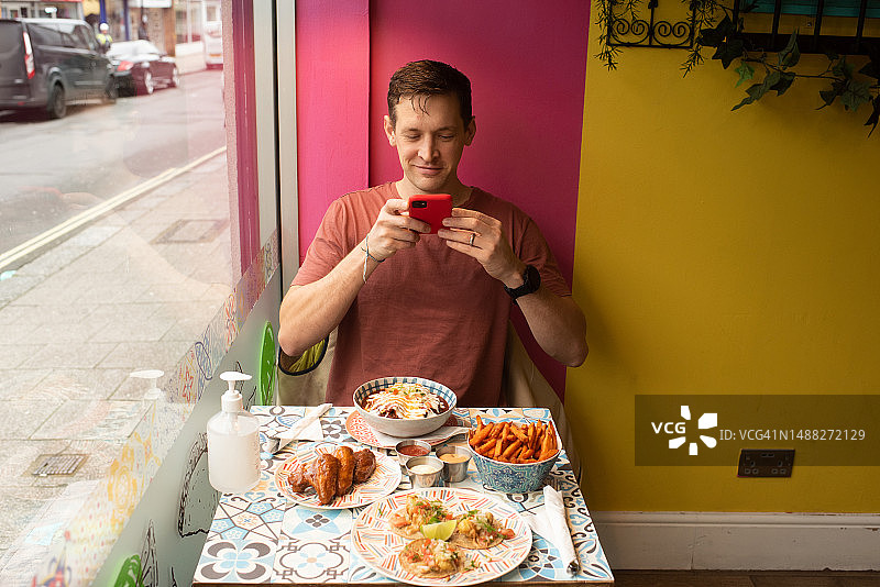 男人在餐厅拍摄墨西哥食物图片素材
