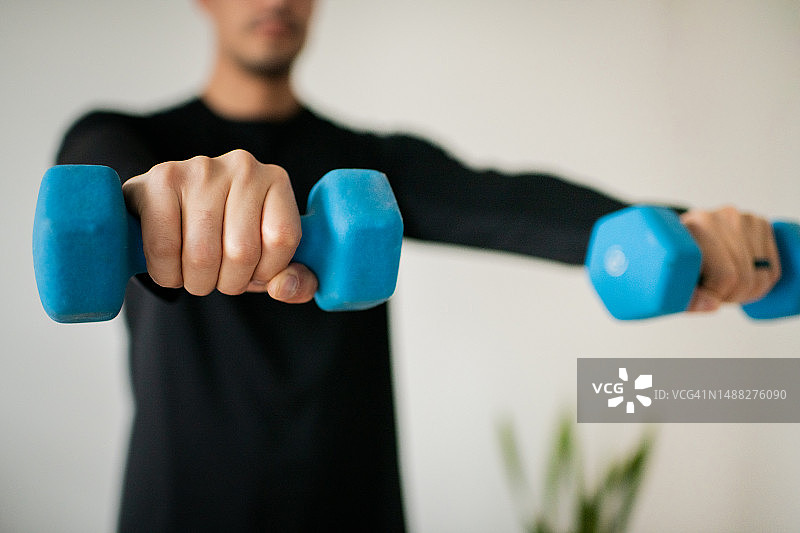 在家举哑铃的年轻男人图片素材