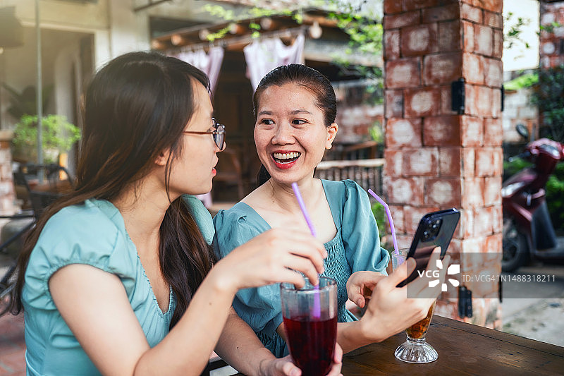 两个女人在越南街头咖啡馆看手机图片素材