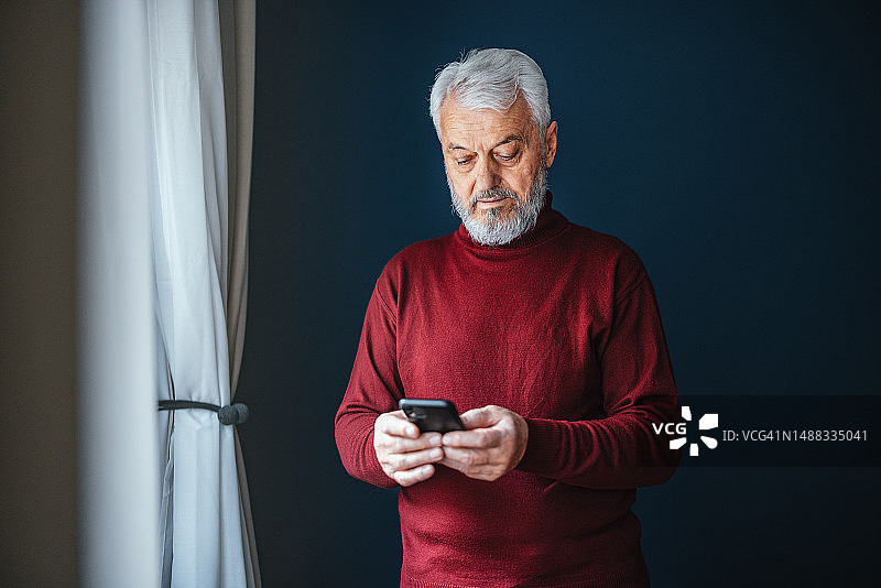 年长的男人在家使用手机图片素材