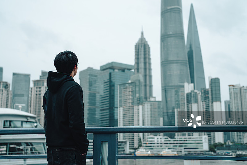 欣赏河畔城市风光的亚洲青年图片素材