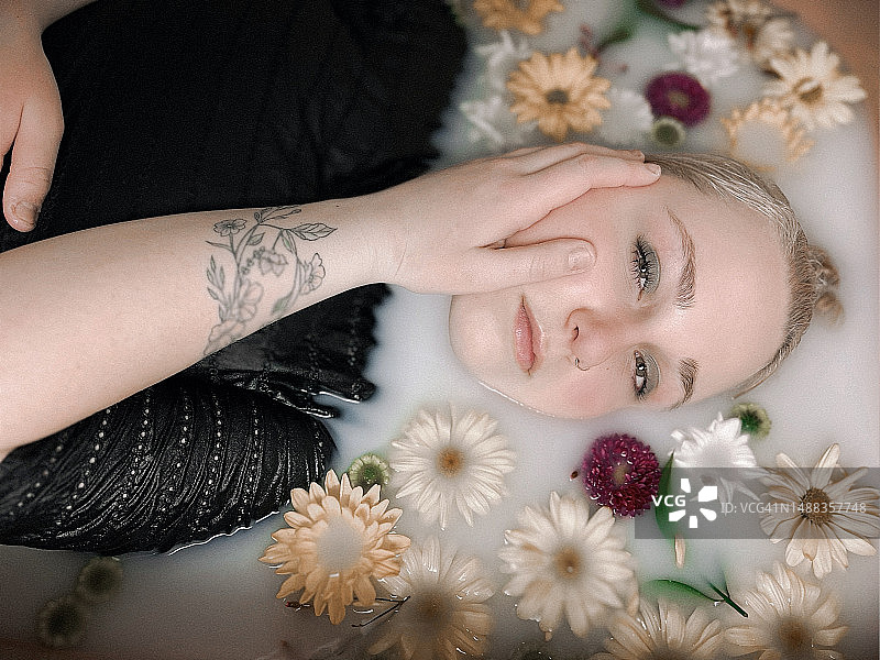 在鲜花牛奶浴中的美丽年轻成年女性图片素材