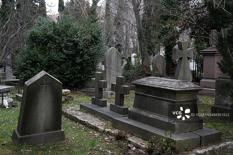 城市公墓：无人看管的旧坟墓，石头墓碑和金属十字架图片素材