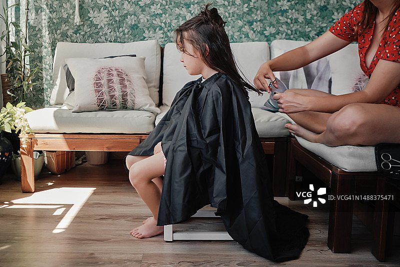 妈妈在家给可爱的小女儿剪头发图片素材