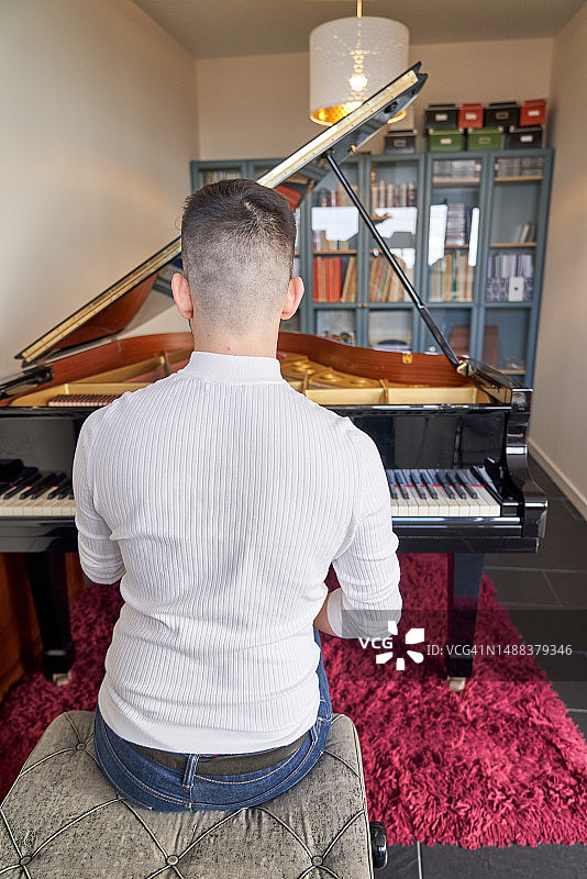 在家弹奏大钢琴的年轻人图片素材