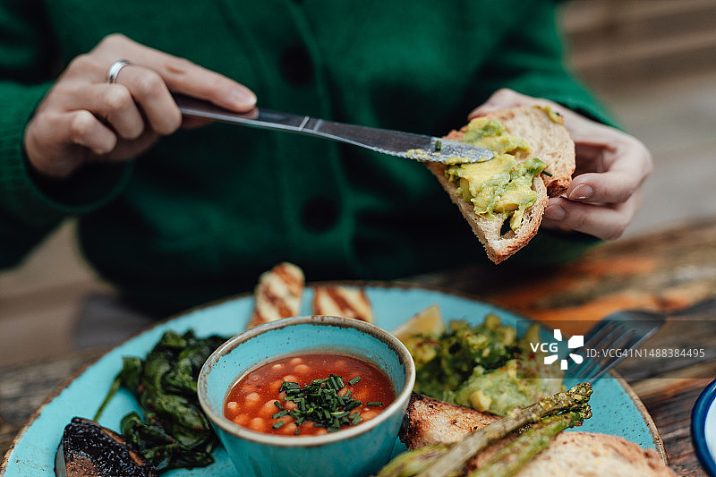 年轻女人在路边咖啡馆享用早餐图片素材