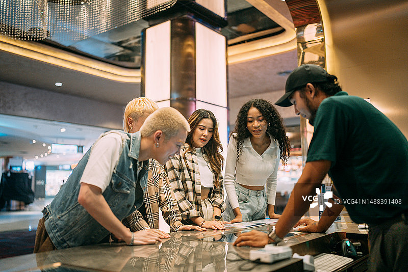 一群朋友在售票柜台前选电影图片素材