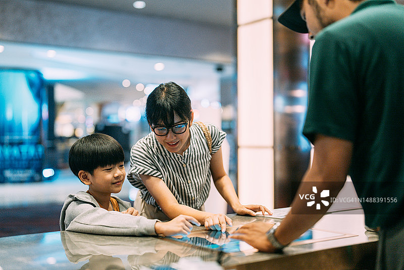 亚洲家庭顾客在电影院售票柜台购买电影票图片素材