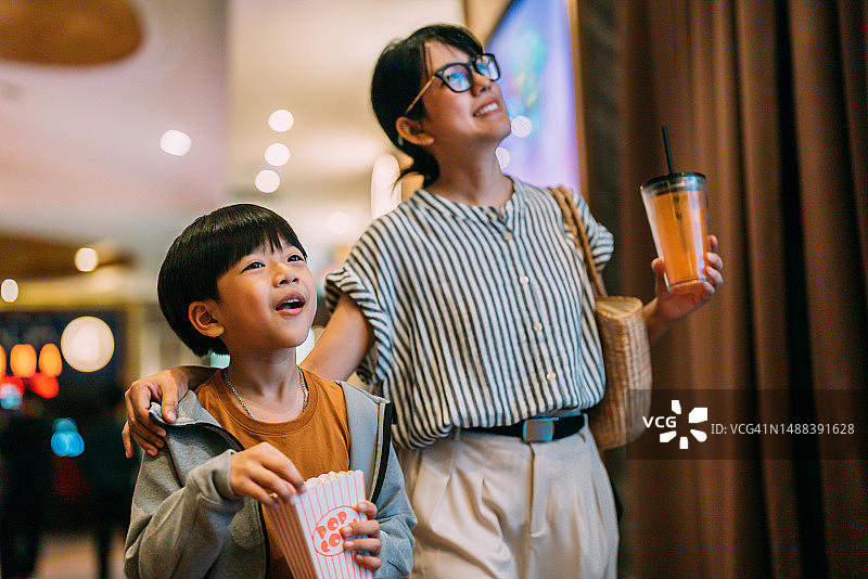 现代亚洲女性和儿子拿着饮料和爆米花去看电影图片素材