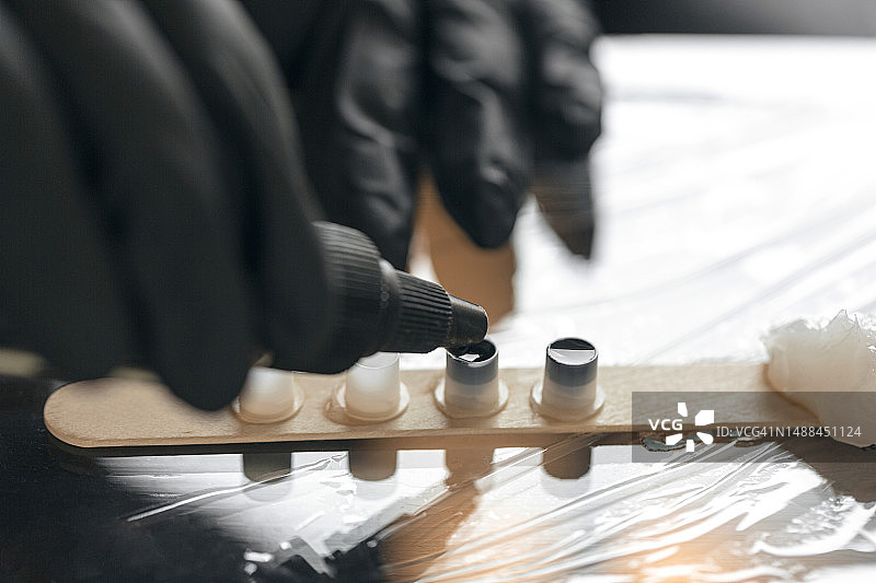 纹身师戴黑色手套拿着颜料瓶倾倒颜料特写：纹身准备过程图片素材