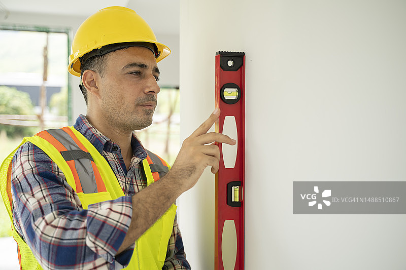 正在检查公寓墙壁的年轻男性建筑工人图片素材