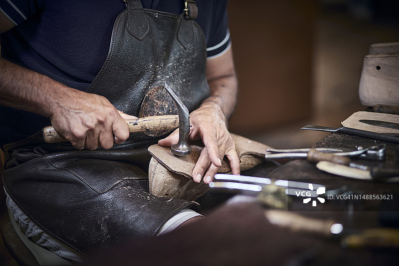 鞋匠在工作室用锤子工作的特写图片素材