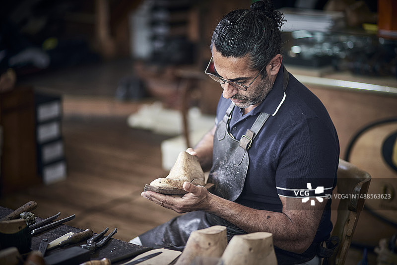 鞋匠在工作室检查鞋楦图片素材