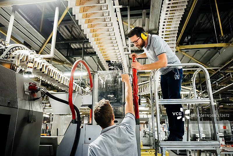 印刷厂里检查传送带的两位工程师图片素材