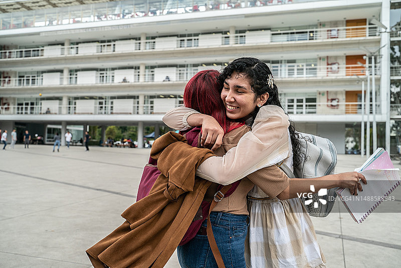在大学校园里拥抱的女大学生朋友图片素材