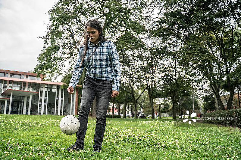 年轻男人在公园踢足球图片素材