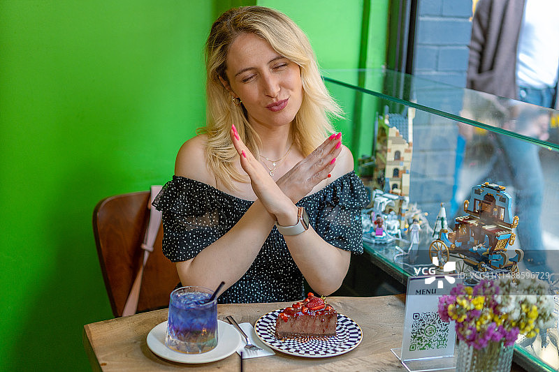 在咖啡馆里拒绝蛋糕的女人图片素材