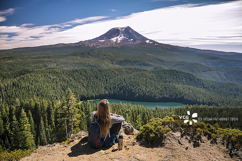 女人坐在悬崖上，背景是亚当斯山图片素材