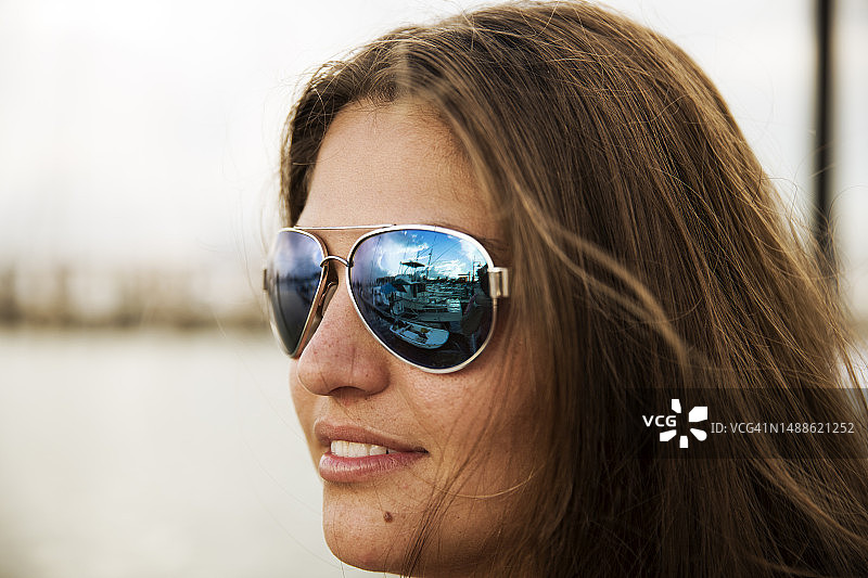 戴着太阳镜，映衬着蓝色风景的年轻长发女子图片素材