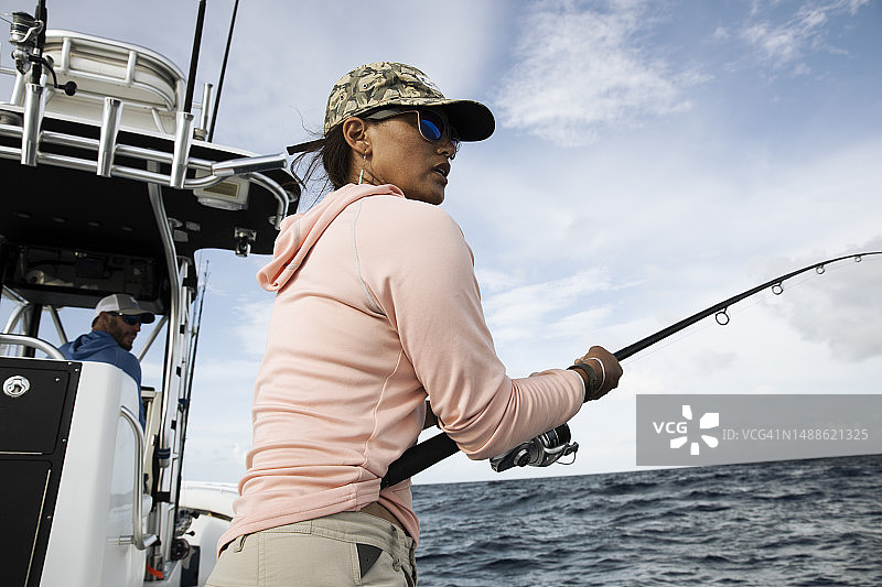 女人在渔船上拿着鱼竿，望着水面图片素材