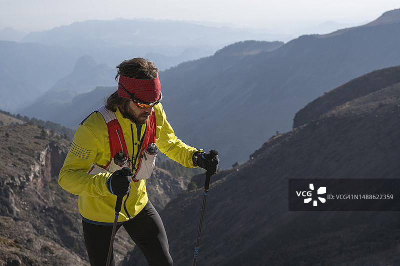 一名男子穿着黄色衣服，用登山杖徒步登上奥里萨巴山图片素材