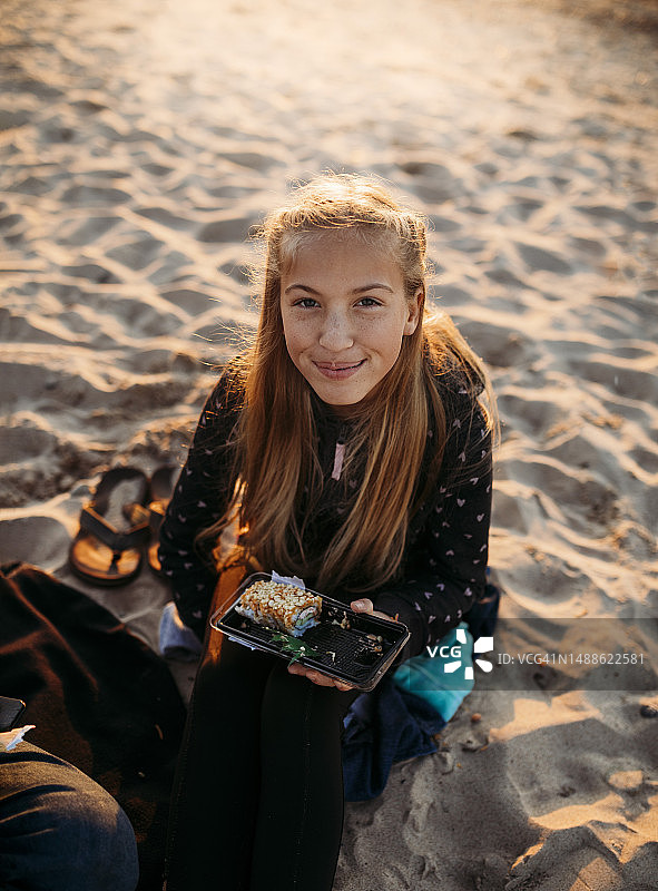 女孩坐在密歇根湖的沙滩上吃寿司图片素材