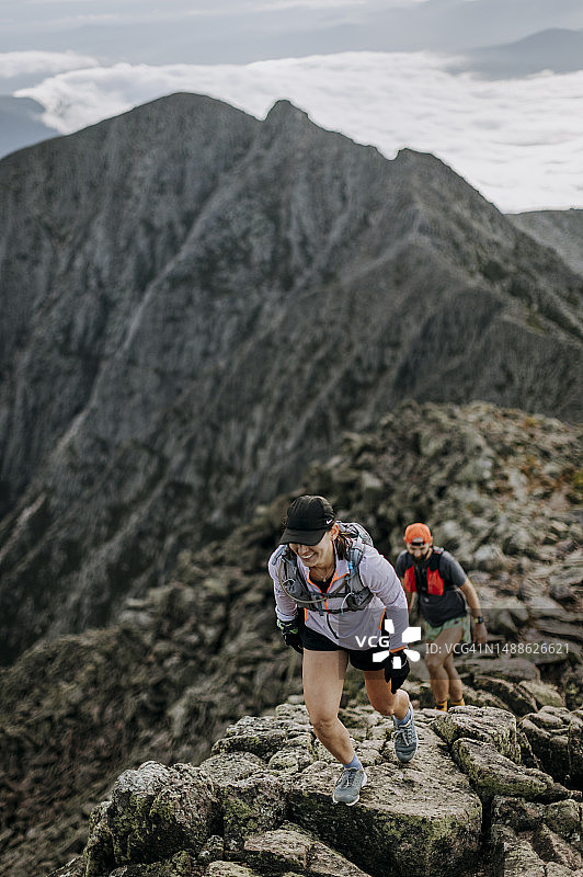女徒步者在缅因州卡塔丁的刀刃边缘引导同伴图片素材