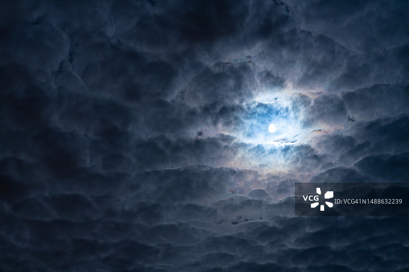 黑色夜空中的月亮和奇异的白色云朵图片素材