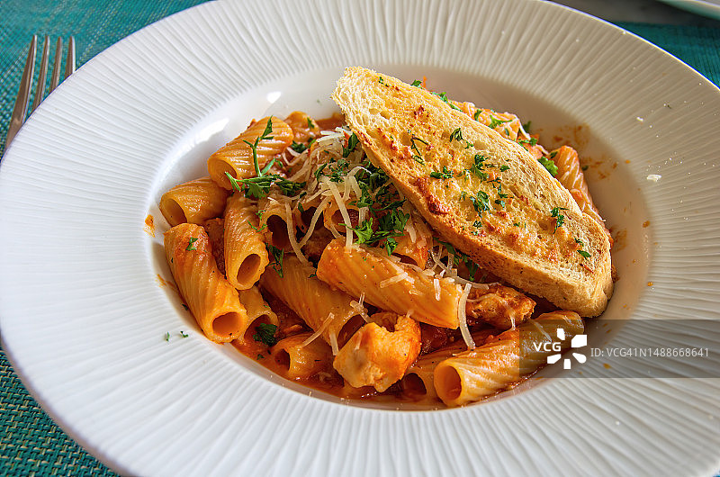 鸡肉、墨西哥辣椒、黄油和香菜烩里加托尼面，配烤奶酪面包片图片素材