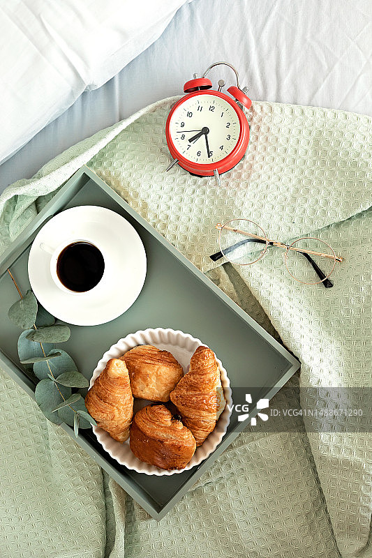 阳光明媚的房间里床边的闹钟和咖啡杯：轻松的早晨开始，积极的一天开始，醒来，新的一天图片素材