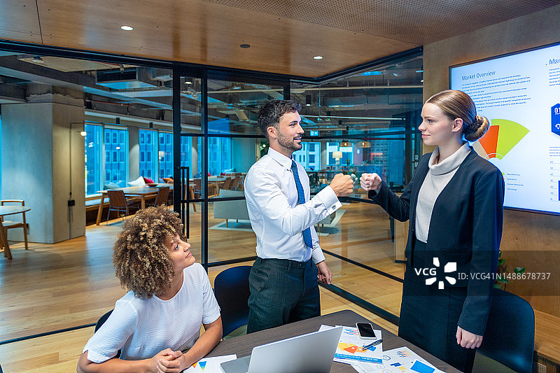 在办公室会议室里与同事碰拳的女商人图片素材