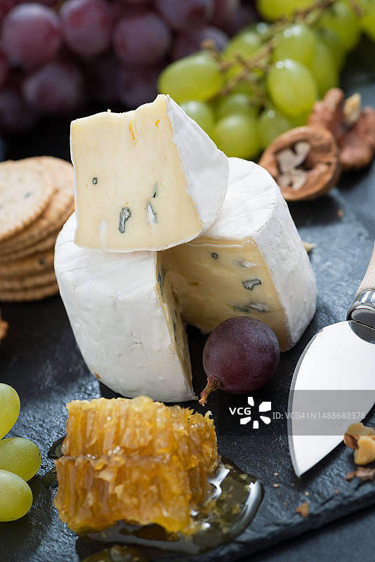 搭配新鲜蜂蜜、葡萄和坚果的卡门贝干酪，特写，竖版图片素材