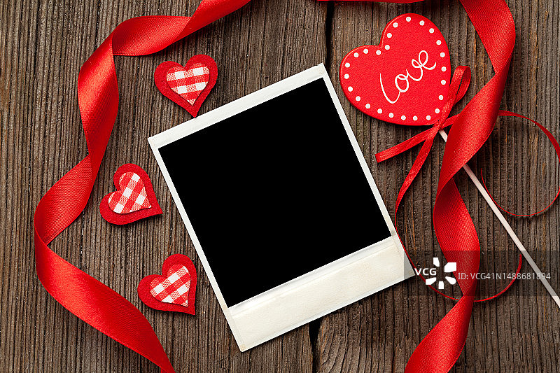 情人节木制背景上的红色心形和丝带宝丽来空相框图片素材
