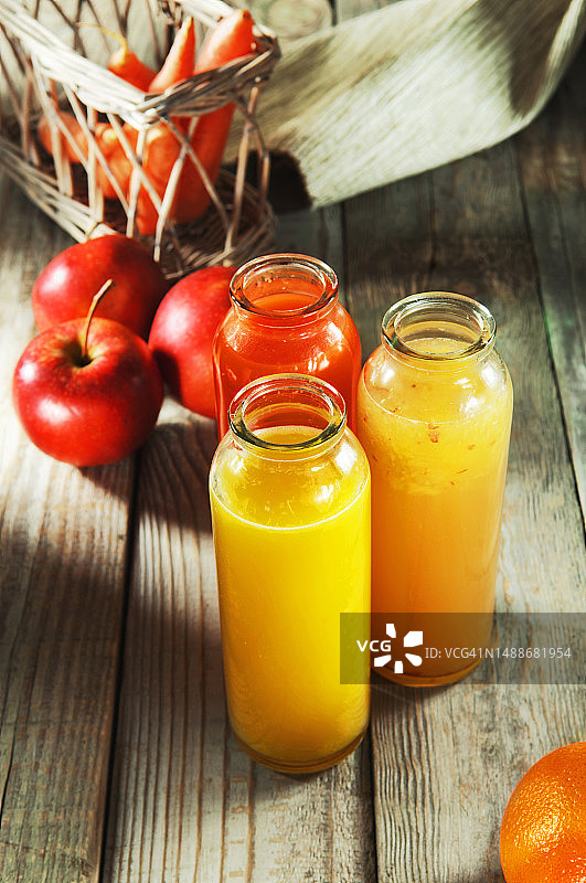 木桌上的鲜榨苹果、胡萝卜和橙汁图片素材