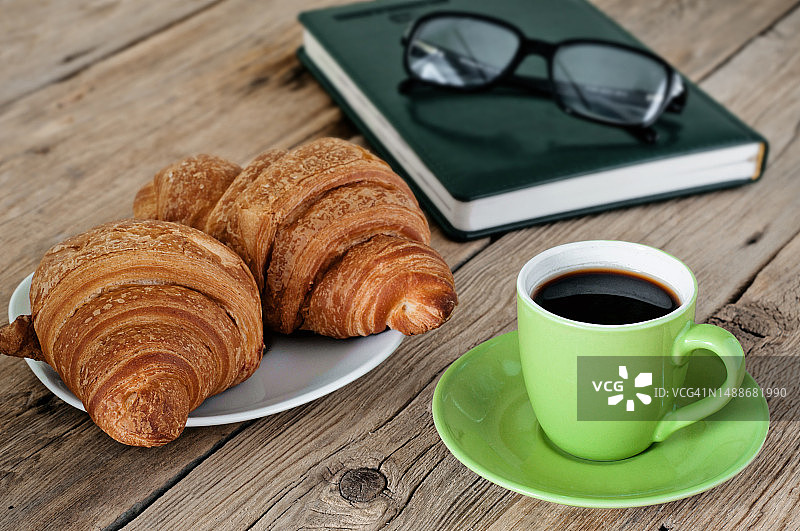 木桌上的咖啡、羊角面包和记事本图片素材