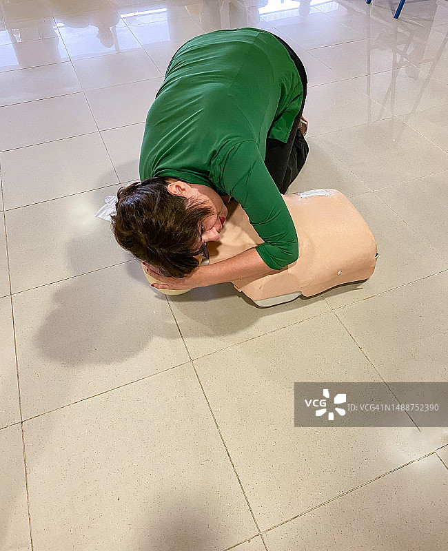 女人在人体模型上练习心肺复苏术。图片素材