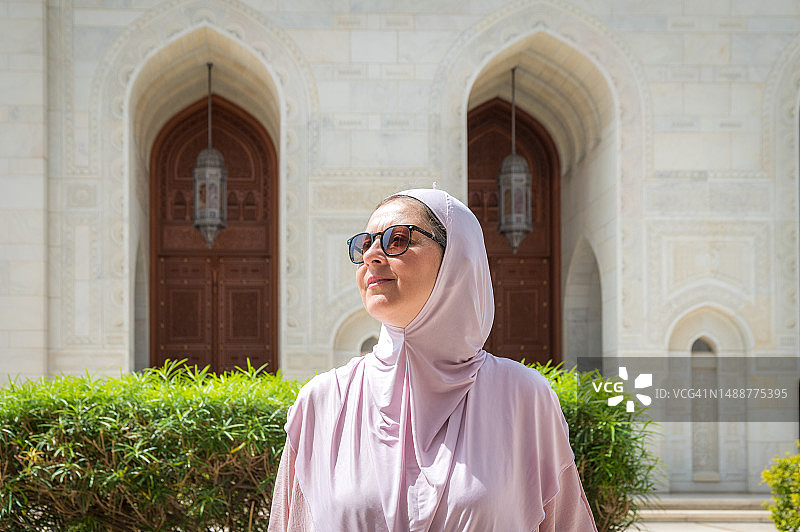 戴着头巾和太阳镜站在阳光下的女人图片素材