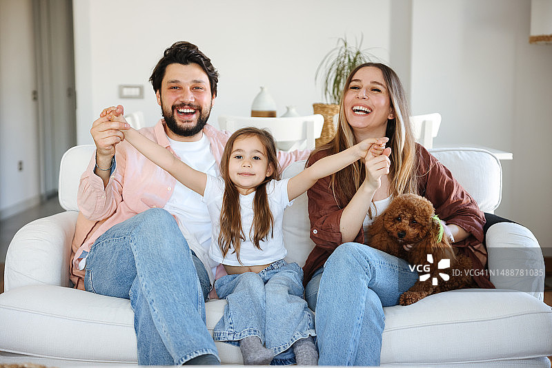 年轻家庭和他们的狗坐在客厅的沙发上图片素材