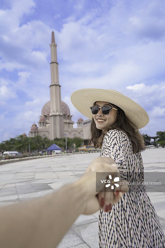 在马来西亚吉隆坡联邦直辖区清真寺外，女人抱着男友对着镜头微笑图片素材