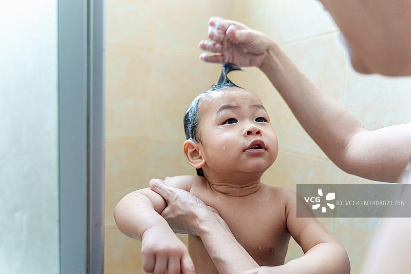 父母在浴室为可爱的幼儿宝宝洗头发，可爱的亚洲新生婴儿享受沐浴放松，父母在家照顾婴儿，家庭亲子生活方式图片素材