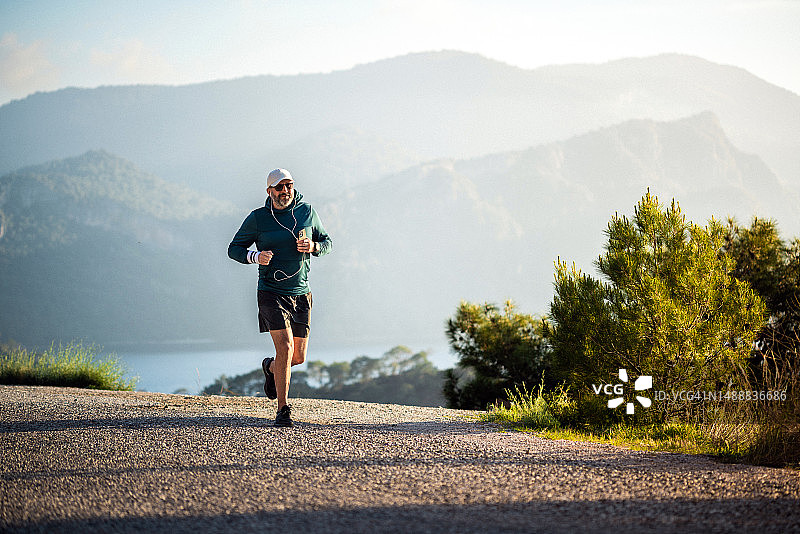 在日落时分在山中慢跑的快乐男人图片素材