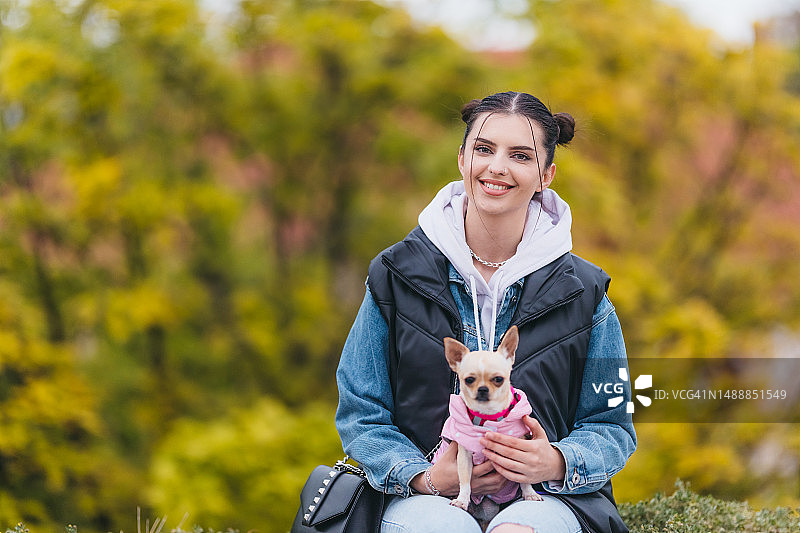 抱着吉娃娃的年轻漂亮女人，彩色背景图片素材