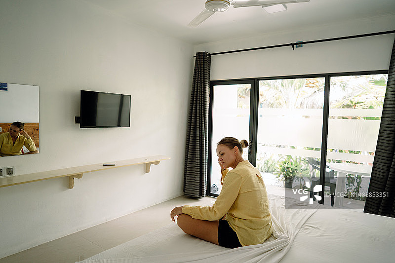 一位穿着黄色毛衣的中年妇女在床上做瑜伽图片素材