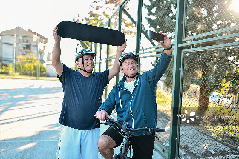 两位老年男性户外滑冰和骑自行车视频会议图片素材