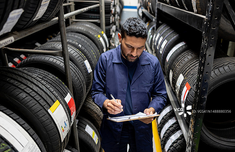 男子在轮胎厂工作时进行库存盘点图片素材