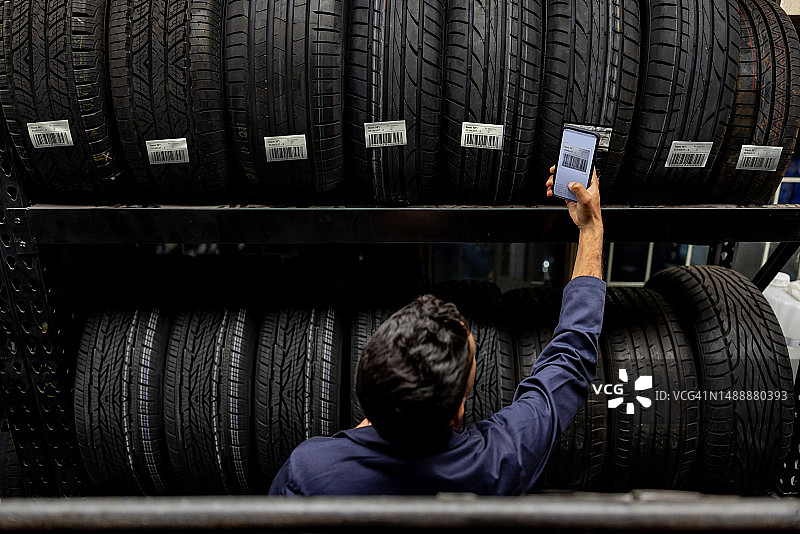 员工在车库商店扫描轮胎上的条形码图片素材