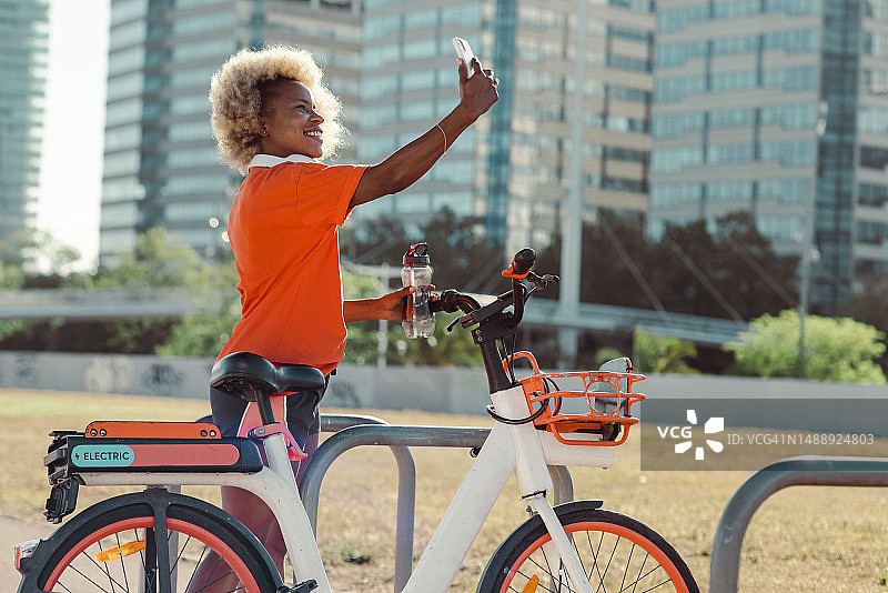 非裔女人穿运动服骑共享单车自拍图片素材