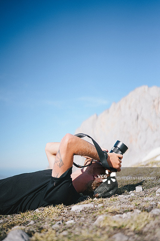摄影师仰卧在山中拍照图片素材