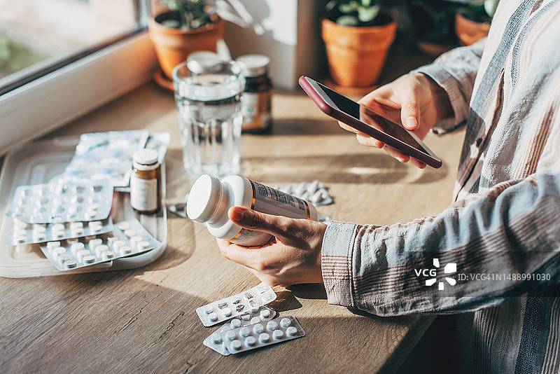 家庭急救箱顶部视图特写：女性的手整齐地放置药物，透明塑料盒内有药品、药丸、注射器和绷带，提供快速的健康安全紧急援助图片素材